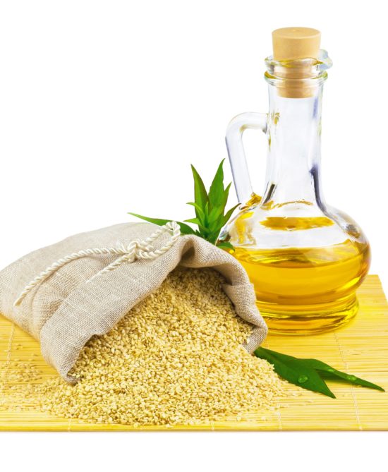 Macro view of sesame seeds in flax sack and glass bottle of sesame oil isolated on white background